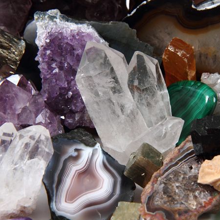 Clear quartz cyrstals, amethyst, jade, onyx, amber, and othim gemstones in a pile.