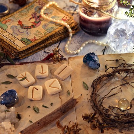 An array of Psychic tools including crystals, tarot cards, runes, gemstones, candles.